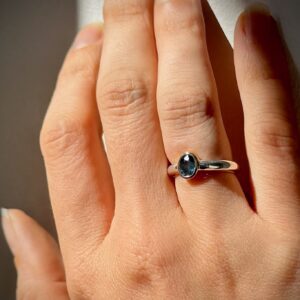 Pebble Ring with a blue Australian sapphire in a gold bezel on a sterling silver band, worn on the hand