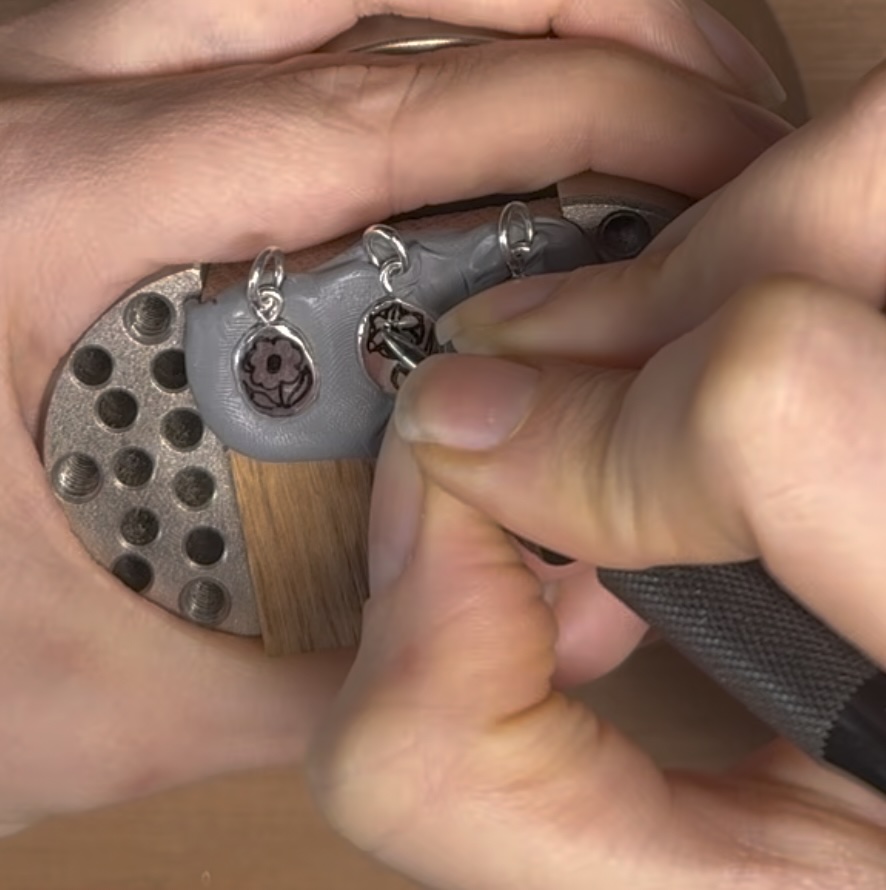 Hands scribing the flower designs onto hand engraved posy charms in sterling silver