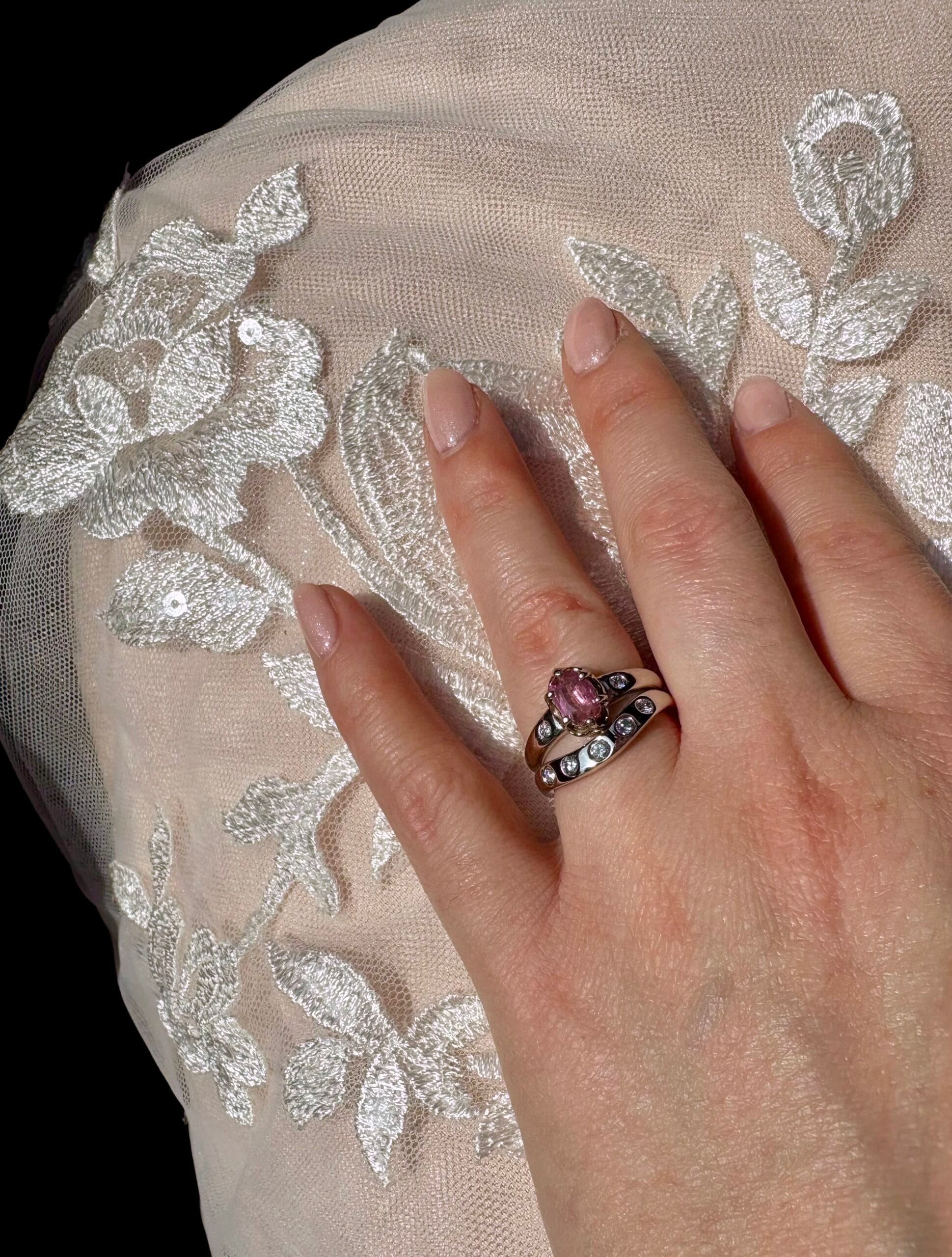 An engagement ring in a ring box, with pink sapphire, white gold, and accent stones